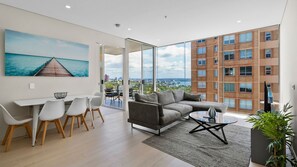 A modern living room with a sofa, coffee table, and dining area. - Bondi Junction Living with Views & Double Parking (New South Wales)