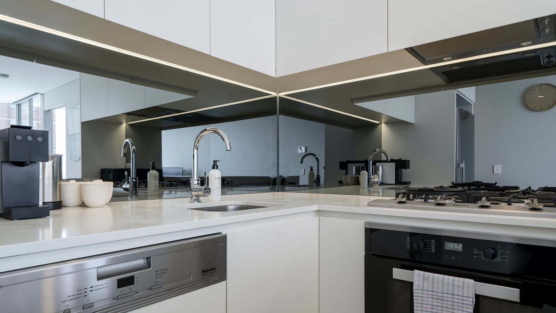Una cocina moderna con una isla central, electrodomésticos de acero inoxidable y un espejo grande.