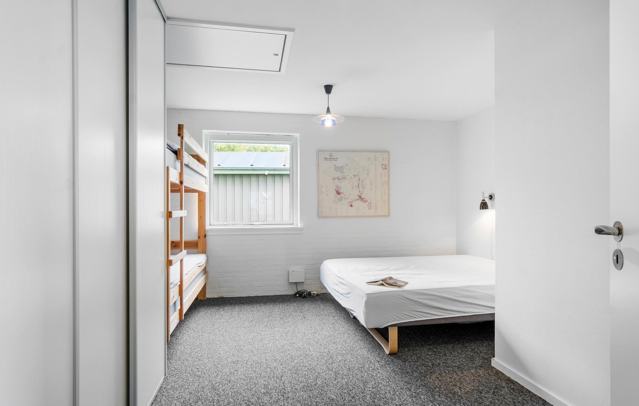 A bedroom with a bunk bed, a single bed, a map on the wall, and a ceiling light.