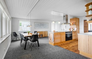 Una cucina moderna con isola centrale, mobili in legno e zona pranzo con sedie.