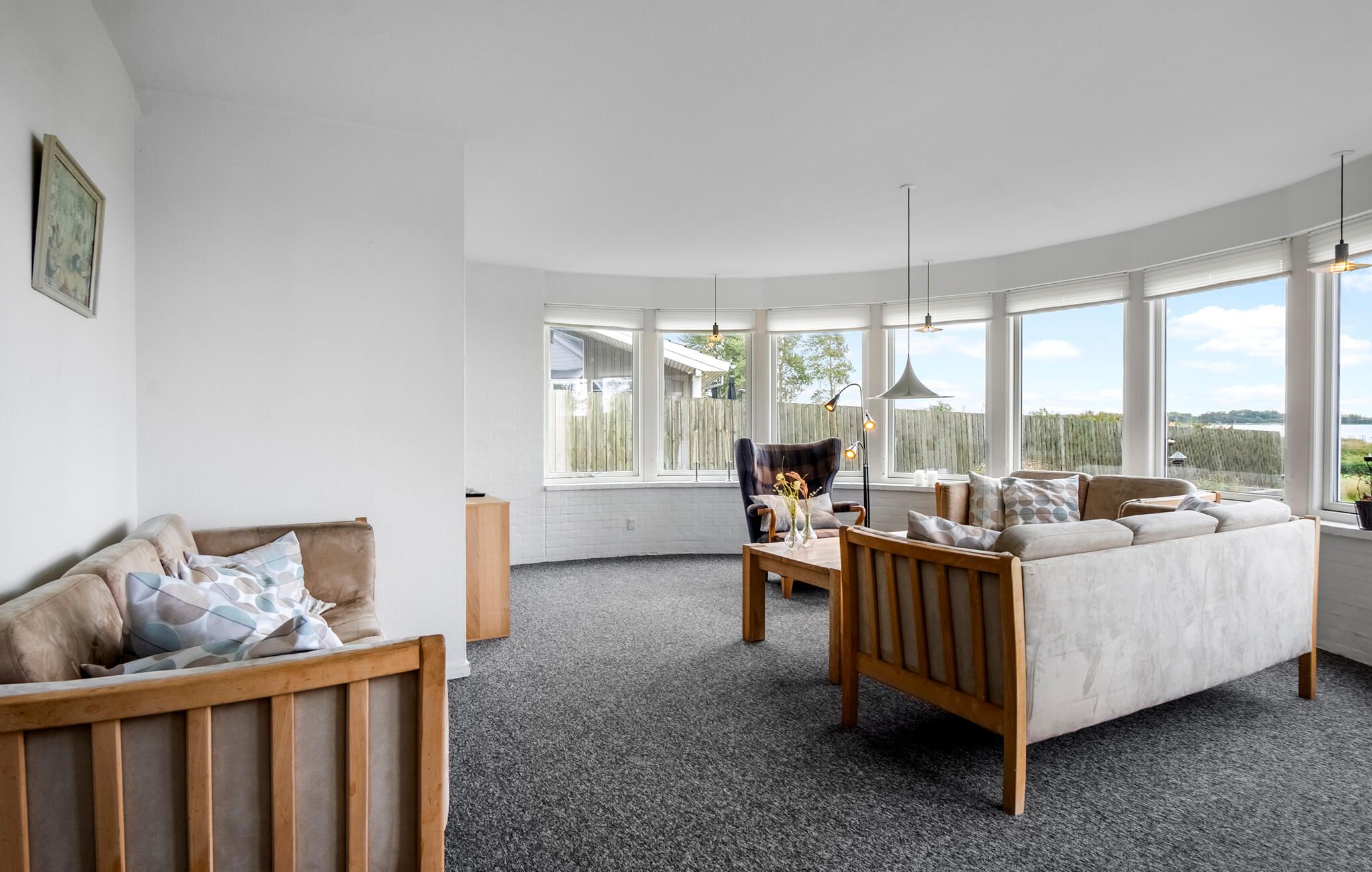 Una sala de estar moderna con techo curvo, un sofá, una silla y vistas al exterior.