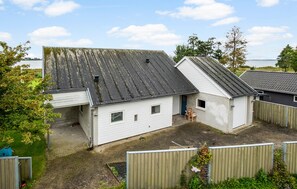 Un edificio a un piano con tetto a falde, un piccolo garage annesso e un cortile recintato.