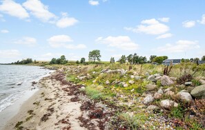 Paesaggio costiero con spiaggia sabbiosa, costa rocciosa e vegetazione.
