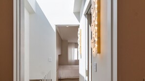 A narrow hallway with a bed at the end, a light fixture on the wall, and a door on the right. - Luxury Paddington Terrace with Courtyard & Balcony (Paddington)