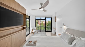 A modern bedroom with a large bed, a ceiling fan, a TV, and a balcony with a view of buildings. - Spacious North Bondi Apt w Balcony near beach (Bondi Beach)