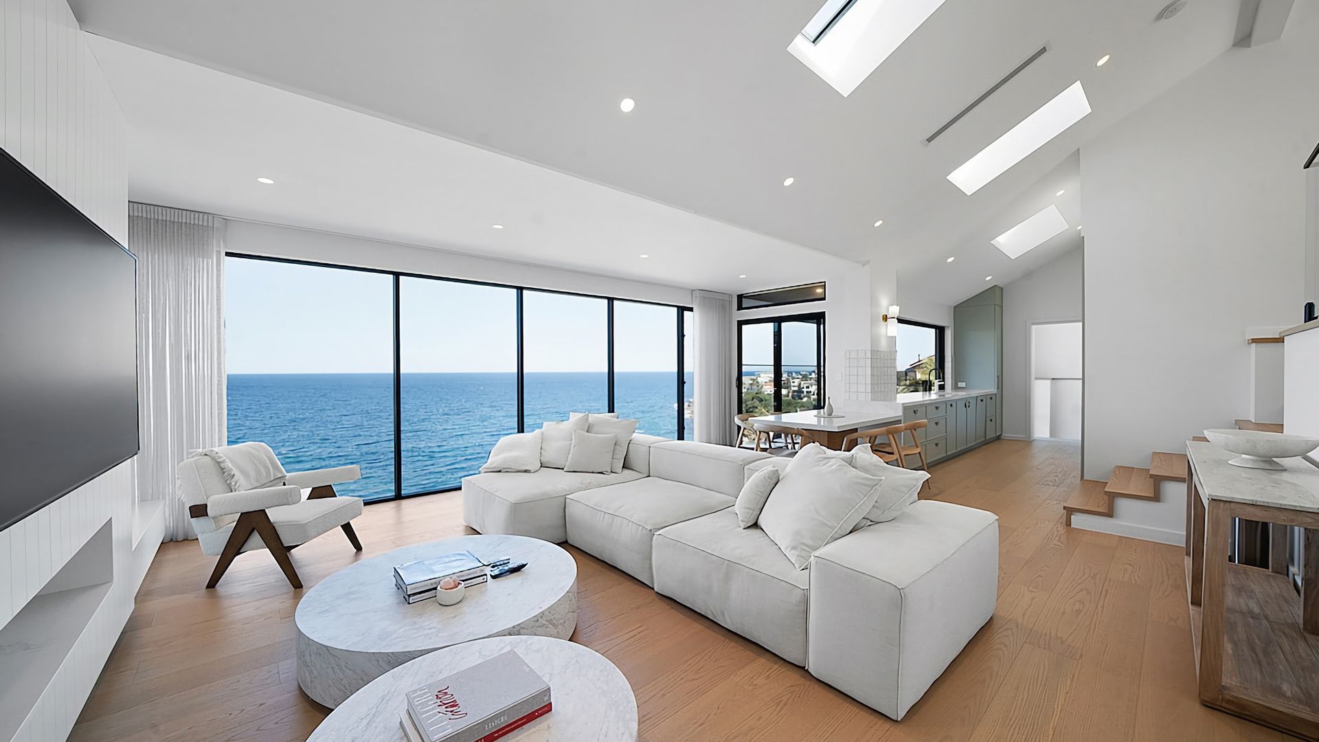 A modern living room with a large sofa, a coffee table, and a view of the sea.