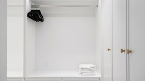 A white wardrobe with a hanging rack and a folded towel on the bottom shelf.