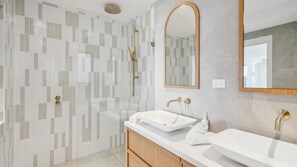 A modern bathroom with a glass shower enclosure, two sinks, and a large mirror. - South Coogee Escape, Heated Pool & Spacious Living (Maroubra)