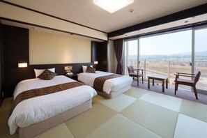 Habitación de hotel con dos camas, un ventanal grande y vistas al paisaje.