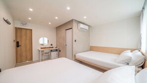 Habitación de hotel con dos camas, un escritorio, un espejo, un armario y un equipo de aire acondicionado.
