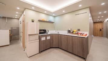 A modern kitchen with a built-in microwave, coffee maker, and a coffee bar.
