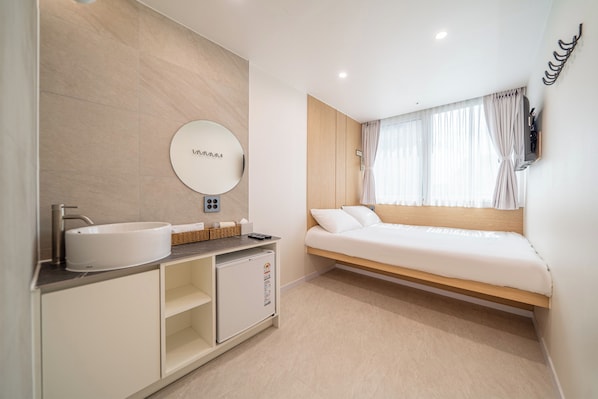 A modern bedroom with a bed, a built-in wardrobe, a round mirror, and a bathroom with a sink and a refrigerator. - Melo Stay Seoul (Seoul)