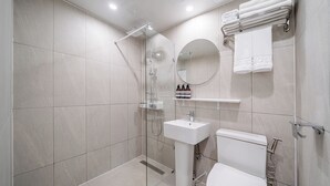 Un baño moderno con ducha envuelta en vidrio, un lavamanos blanco y un inodoro.