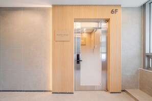 A modern hotel entrance with a wooden panel design, a sign indicating 'melo stay Seoul', and a door marked with the number '6F'. - Melo Stay Seoul (Seoul)