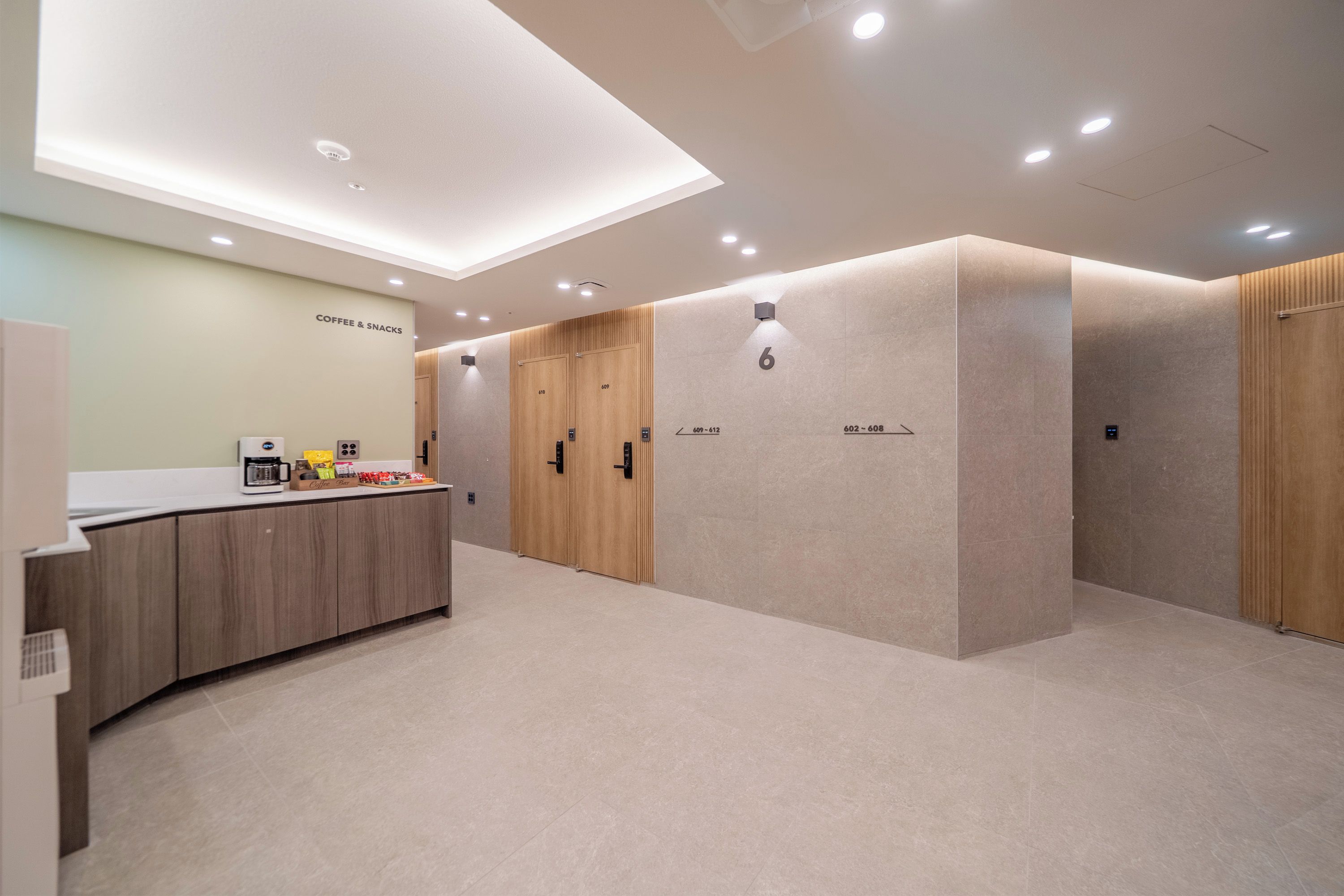 A modern hotel lobby with a coffee station, wooden lockers, and a clean, minimalist design.