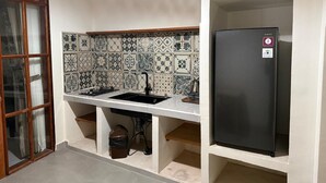 Una cocina con salpicadero de azulejos, un refrigerador negro y un lavamanos con grifo.