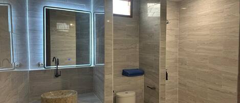 A modern bathroom with a built-in sink, a toilet, and a shower area.
