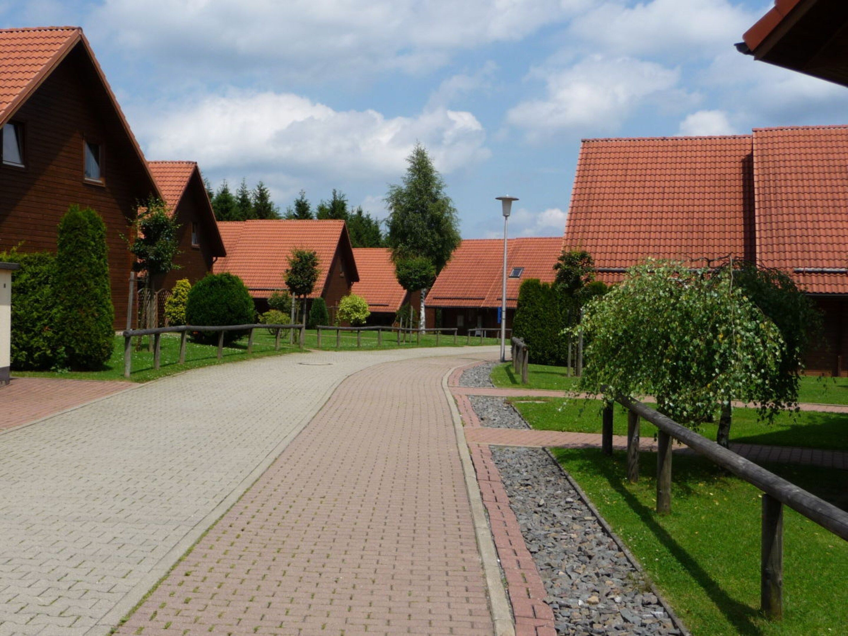 A pathway leading to a row of red-roofed buildings, likely a hotel or resort.