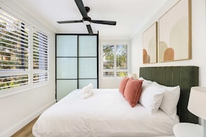 A hotel room with a bed, a ceiling fan, a window with blinds, and artwork on the wall. - The Albion Courtyard, Surry Hills (Surry Hills)