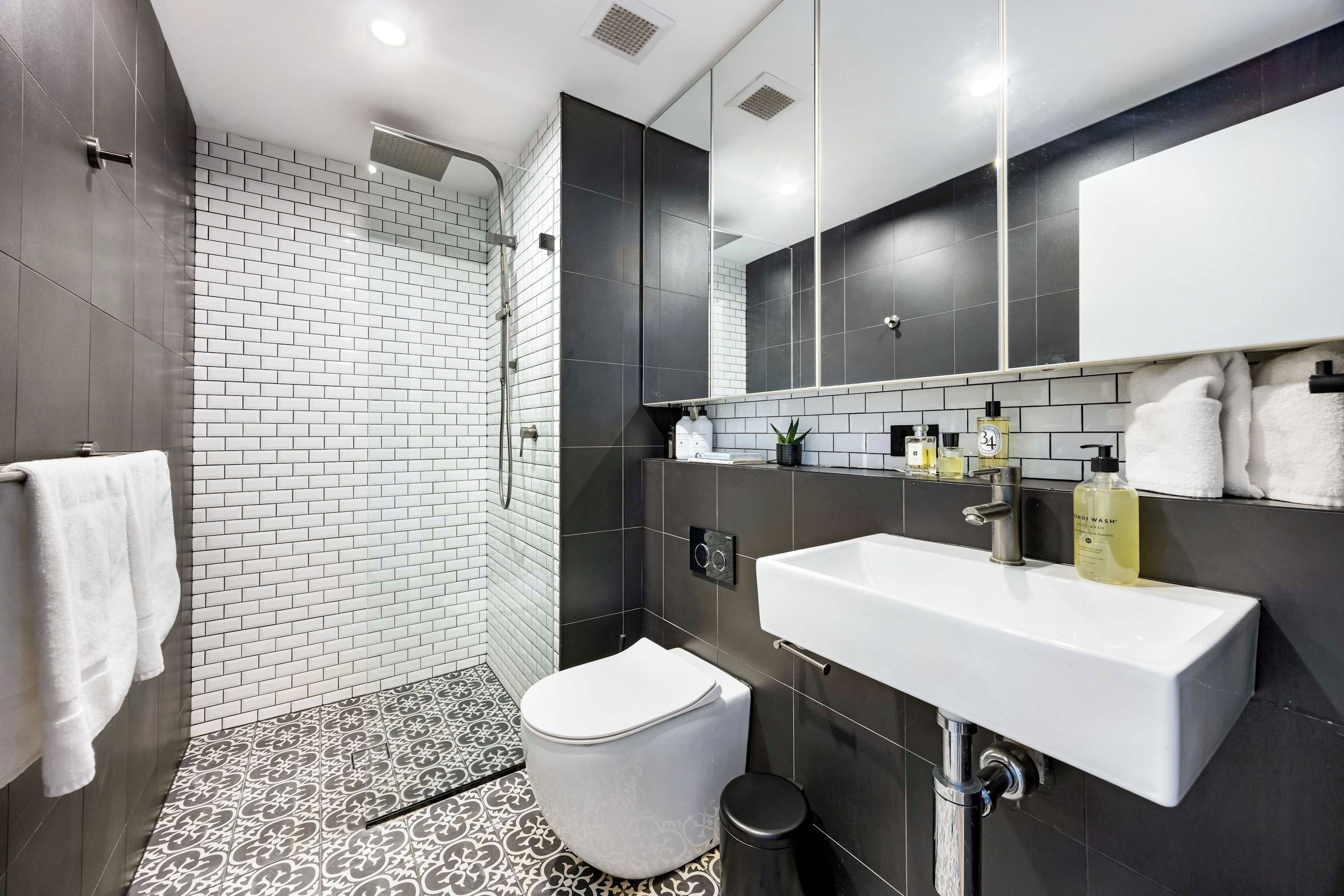 A modern bathroom with a shower, toilet, and sink.