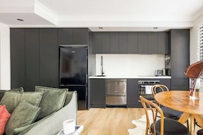 A modern kitchen with dark cabinetry, a stainless steel refrigerator, and a built-in oven. - The Albion Courtyard, Surry Hills (Surry Hills)