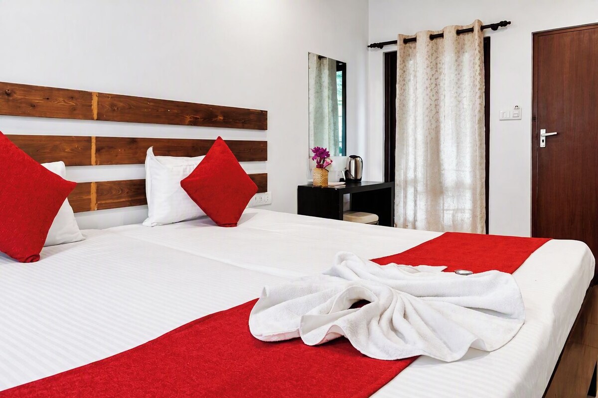 Habitación de hotel con una cama, almohadas rojas, una manta roja y una toalla sobre la cama.