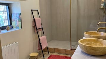 Une salle de bain équipée d’une douche, de toilettes, d’un bidet, d’un lavabo avec un grand bac, d’un porte-serviettes et d’une fenêtre décorée d’œuvres d’art.