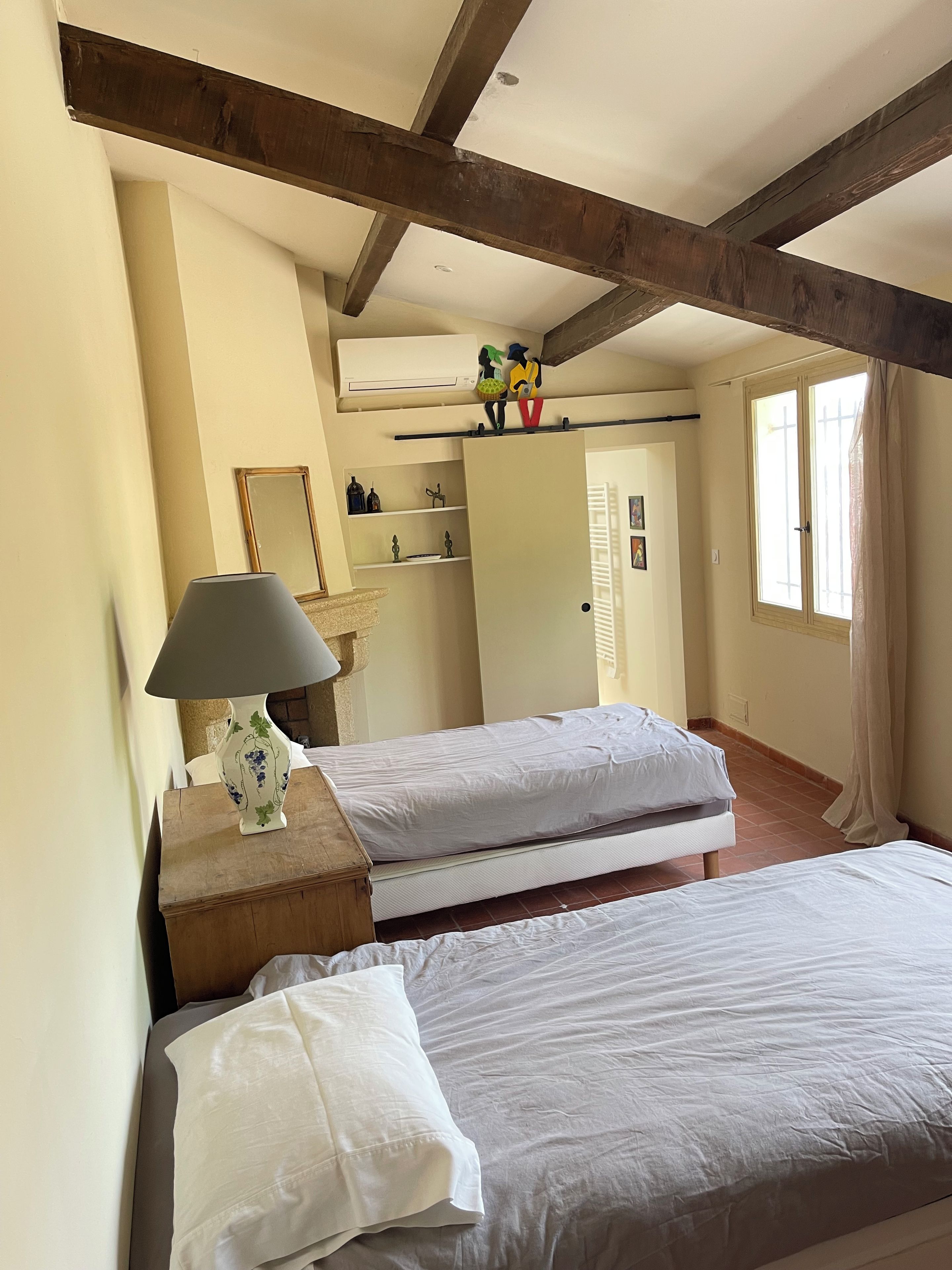 Ein Zimmer mit zwei Betten, einer Lampe, einem Kleiderschrank und einem fenster mit Vorhängen.