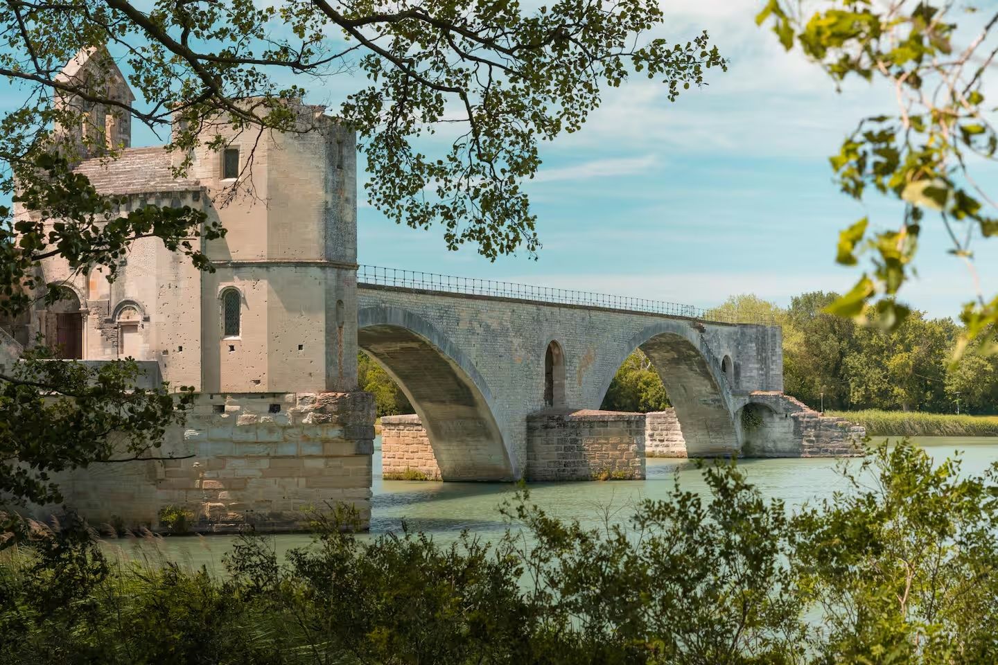 A stone bridge over a river with a building on the left.