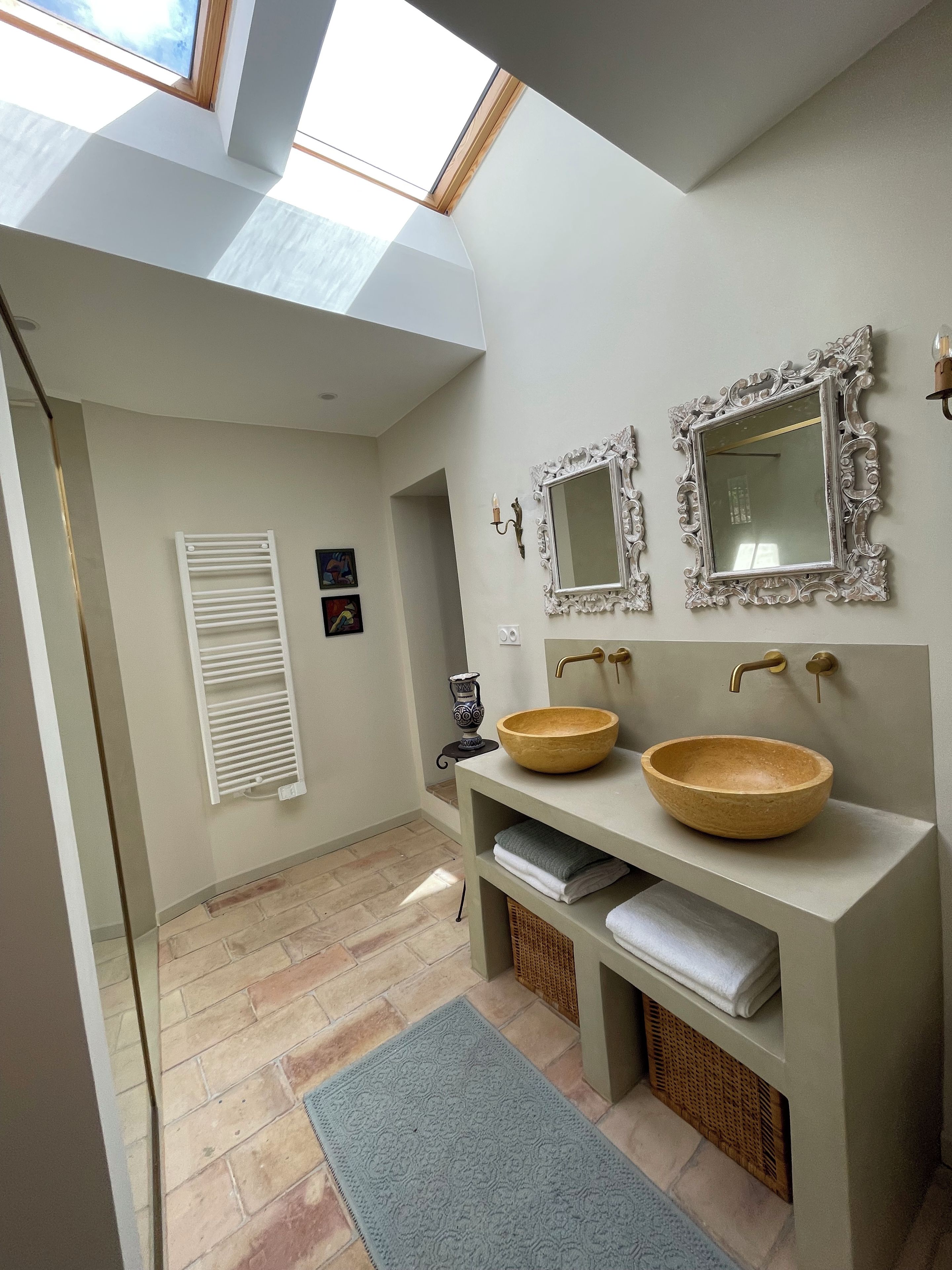 Une salle de bain moderne dotée de fenêtres de toit, de deux vasques avec des récipients en bois et de miroirs décoratifs.