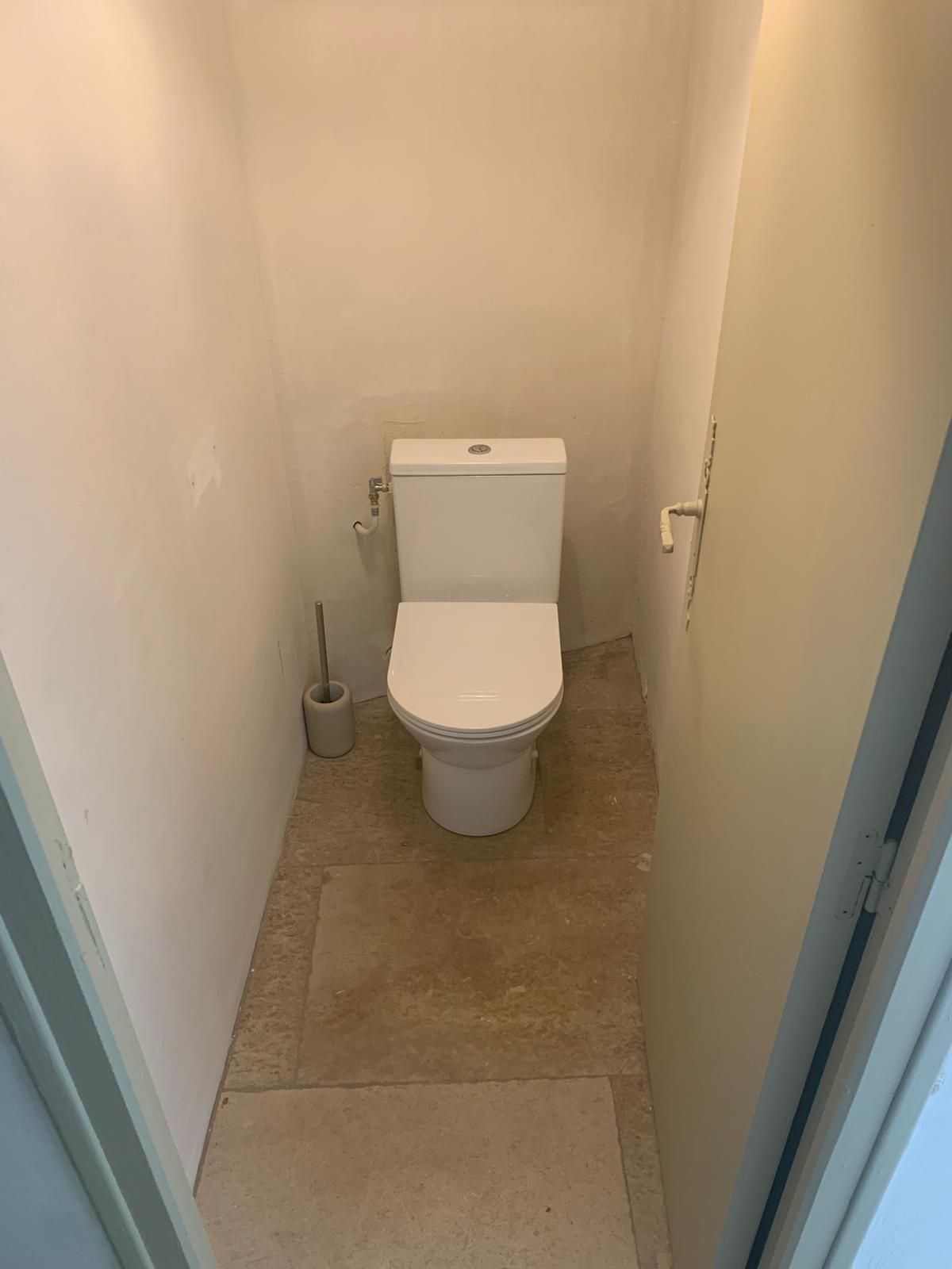 A small, narrow bathroom with a toilet, a bidet, and a toilet paper holder.