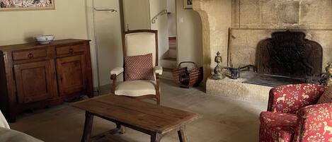 A traditional living room with a fireplace, wooden furniture, and a staircase.