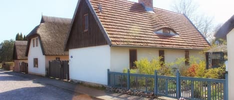 A traditional European-style building with a steeply pitched roof and a thatched roof extension.