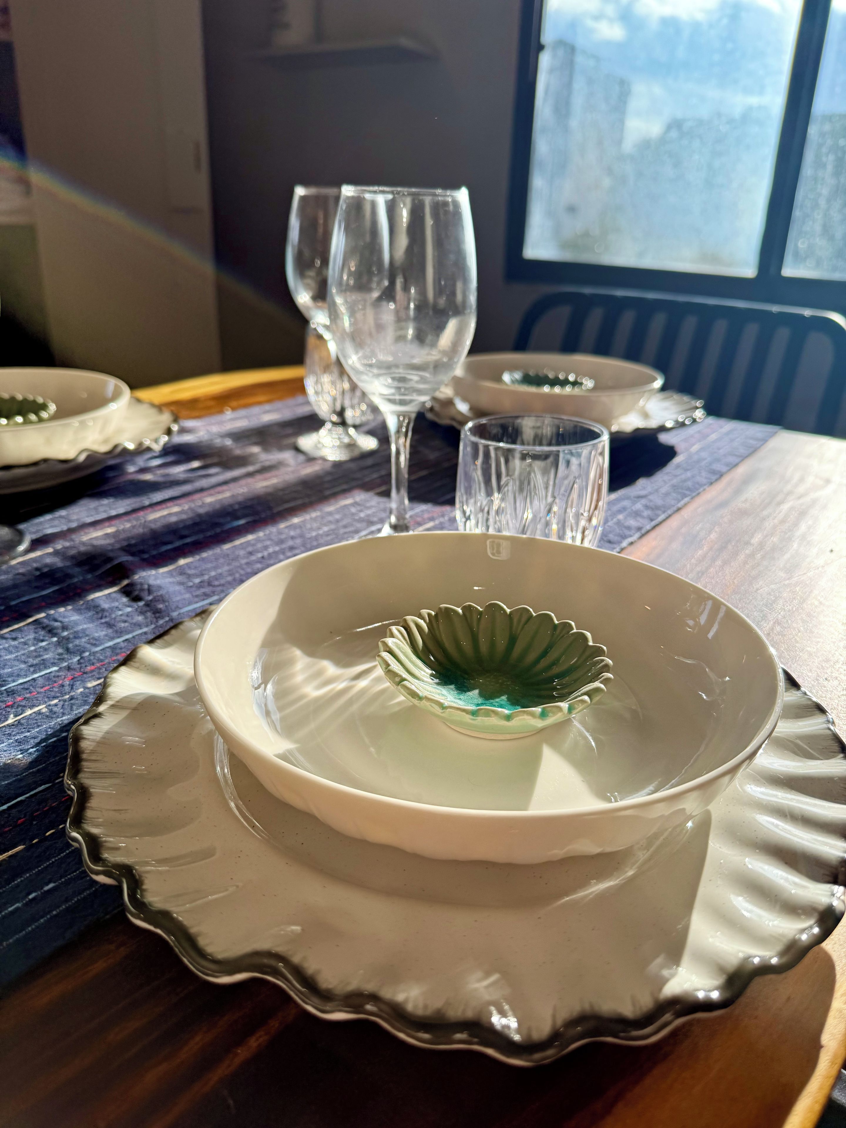 A dining table with plates, glasses, and a window in the background.