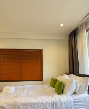 A hotel room with a bed, pillows, a window with curtains, and a ceiling light. - Zzz at Nimman : 3 Floors Cafe Townhouse with Rooftop View (Suthep)