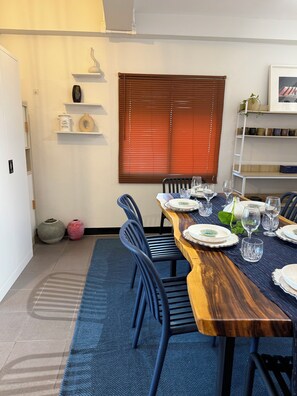 A dining area with a long wooden table set for six, surrounded by blue chairs. - Zzz at Nimman : 3 Floors Cafe Townhouse with Rooftop View (Suthep)