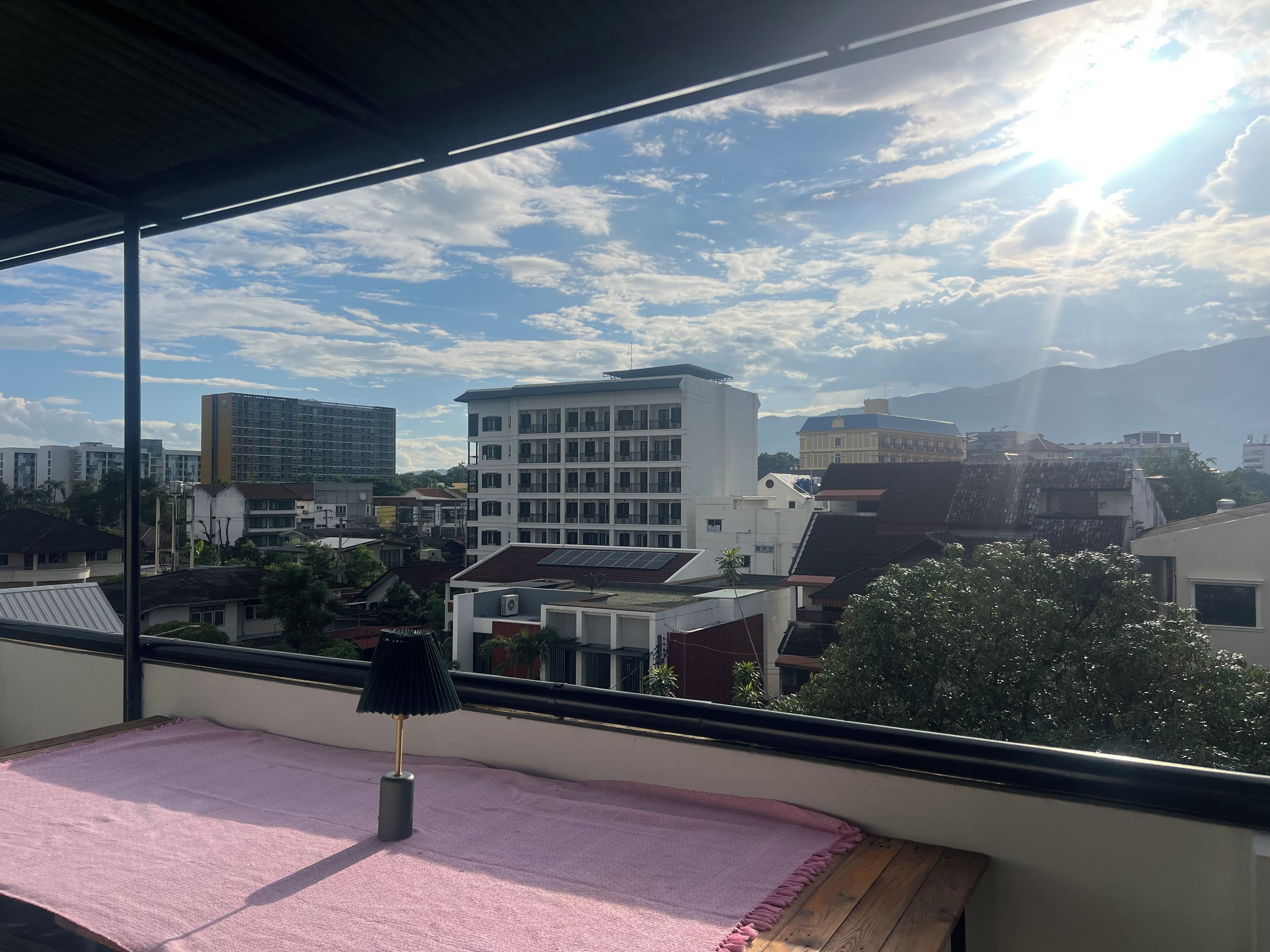 Un balcón con vista a un paisaje urbano, que incluye edificios y montañas.