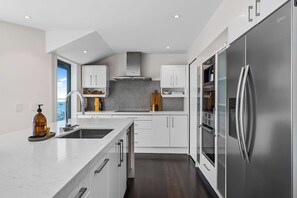 Eine moderne Küche mit weißen Schränken, einem Edelstahlkühlschrank und einem eingebauten Backofen.