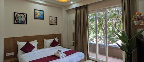 A modern hotel room with a large bed, ceiling fan, recessed lighting, and a view of the outdoors.