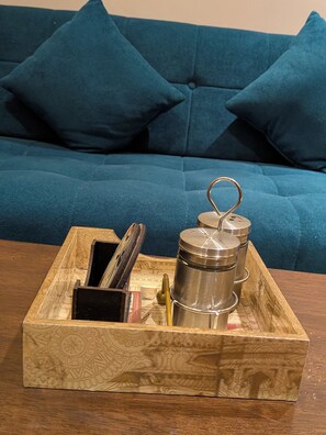 Una bandeja de madera con un recipiente metálico, un bolígrafo y un portaletras sobre una mesa.