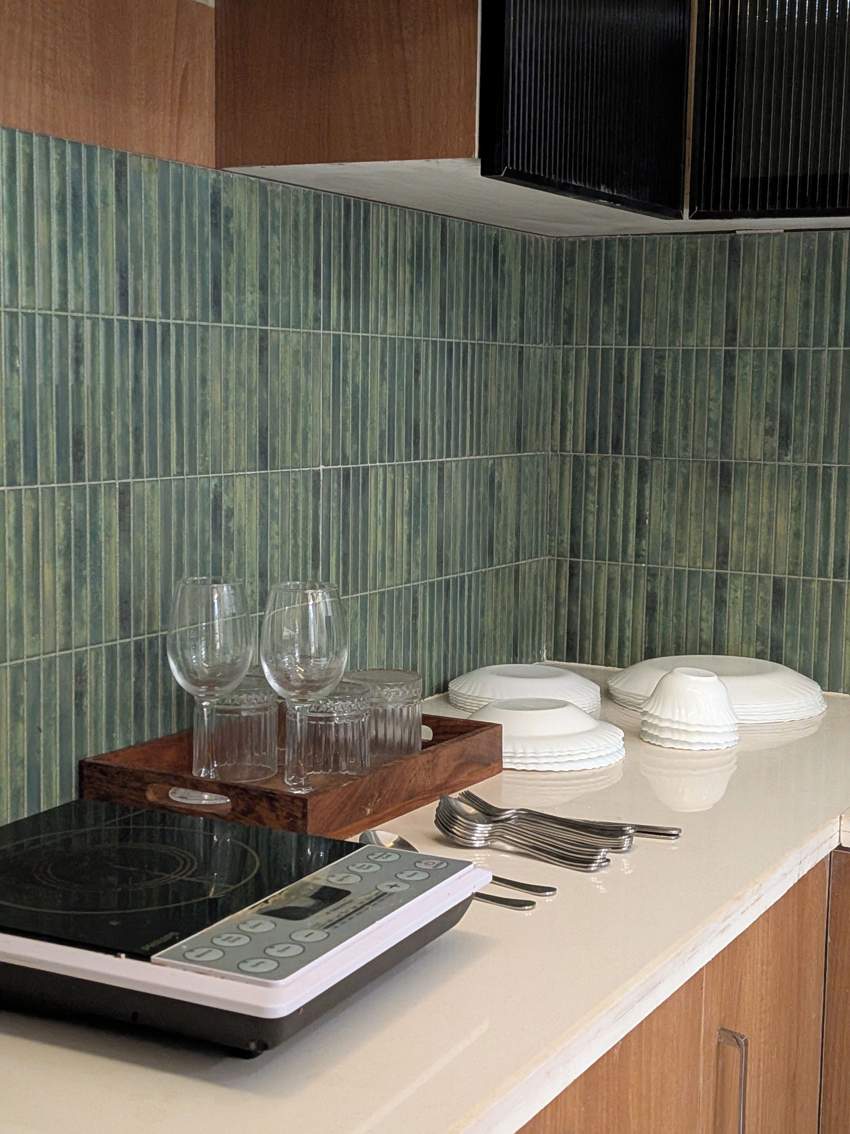 A kitchen counter with a rice cooker, wine glasses, and stacked plates.