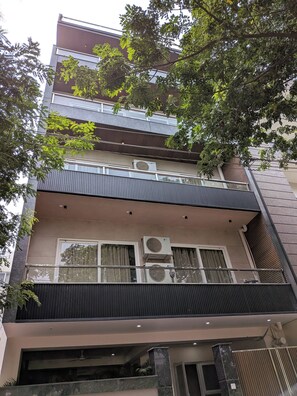 Edifício com várias andares, varandas, aparelhos de ar condicionado e design arquitetônico moderno.