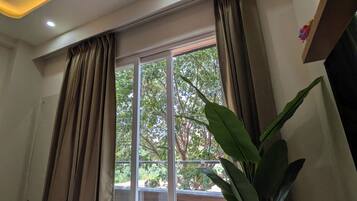 A hotel room with a large sliding glass door, a potted plant, and a ceiling with recessed lighting.