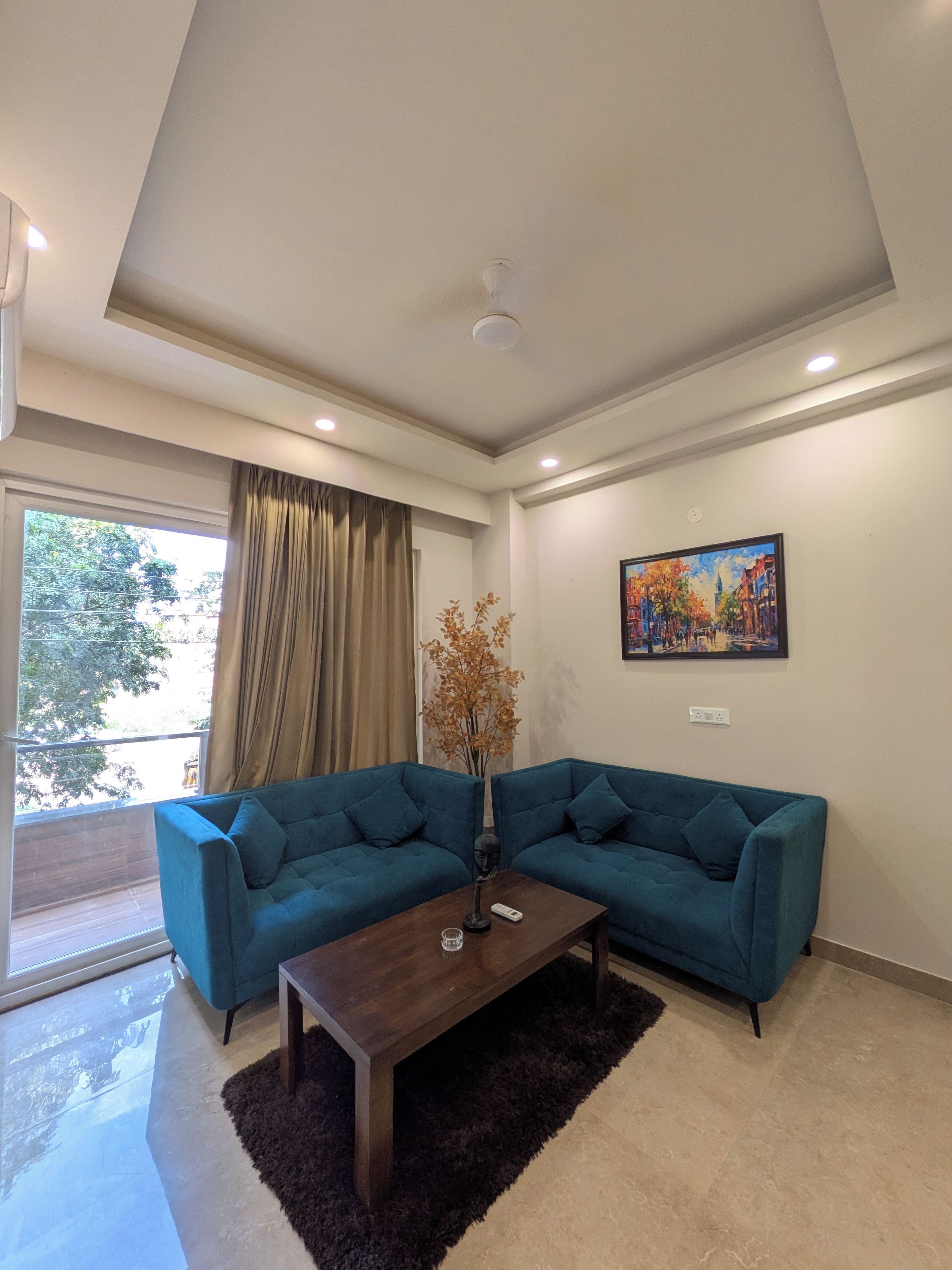 A modern living room with a sectional sofa, a coffee table, a painting on the wall, and a window with curtains.