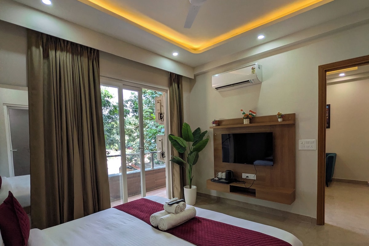 A hotel room with a bed, curtains, a ceiling fan, an air conditioning unit, a television, and a potted plant.
