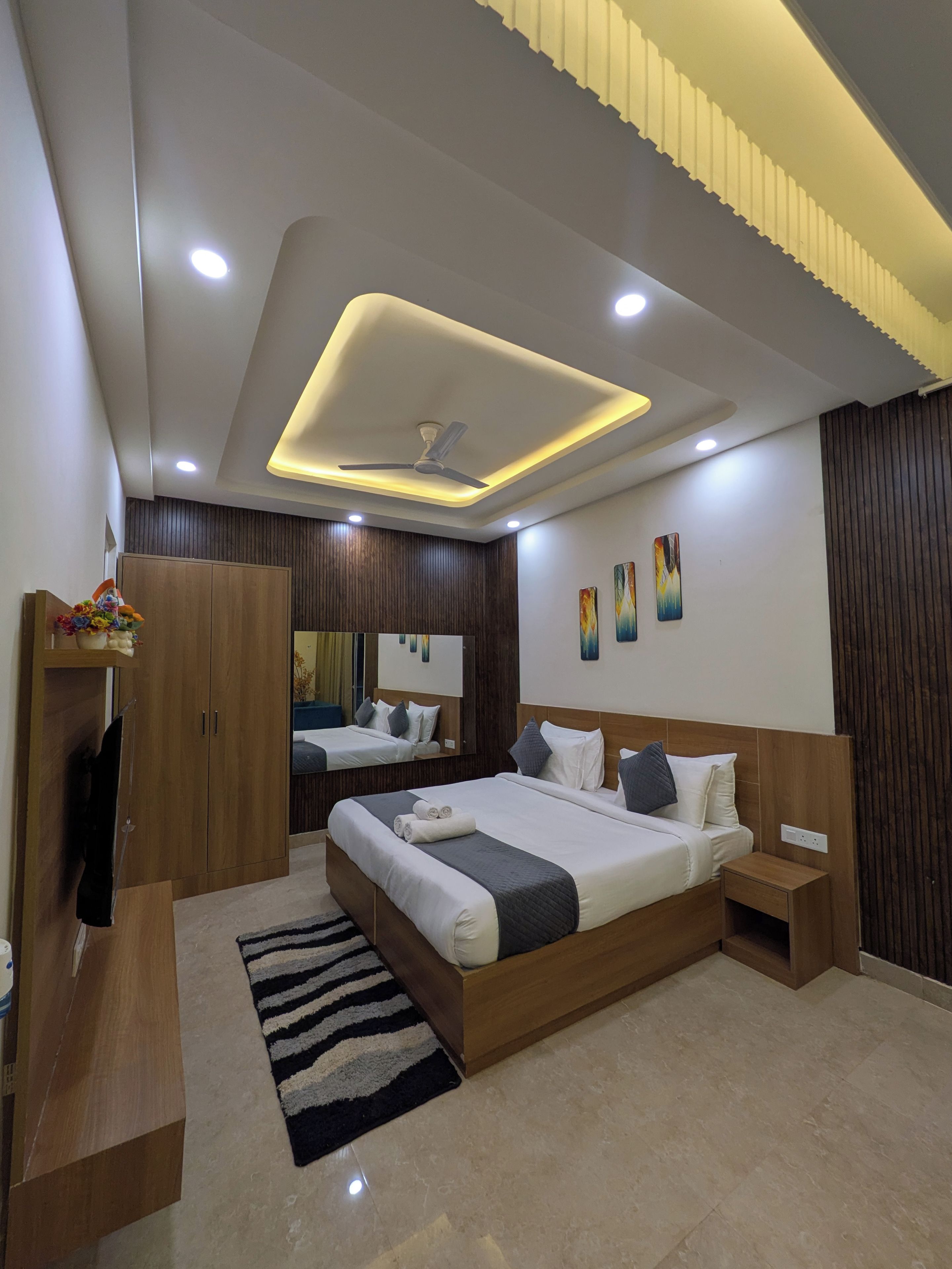 A modern bedroom with a bed, bedside tables, a wardrobe, a mirror, and a ceiling fan.