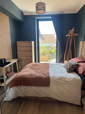 A bedroom with a bed, a wooden dresser, a hanging chair, and a view of the outside.