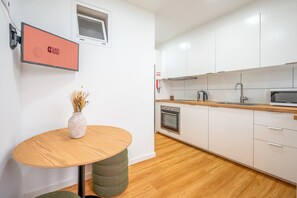 Une cuisine moderne avec des armoires blanches, un plan de travail en bois, un four encastré et un four à micro-ondes.