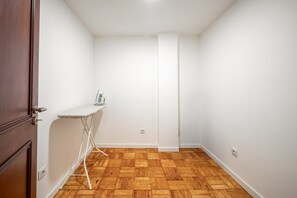 Ein Zimmer mit Holzdielenboden, einem weißen Bügelbrett und einer geschlossenen Tür.