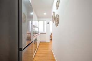 A modern kitchen with white cabinets, a stainless steel refrigerator, and a wooden floor. - GuestReady-Charming Lisbon Retreat (Lisbon)